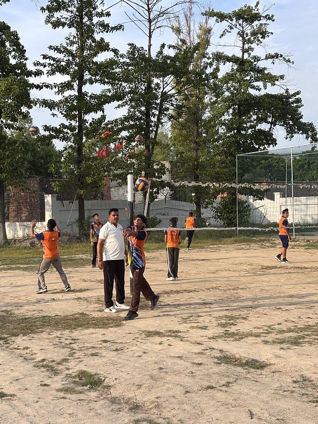 Students in team bibs on the training ground beside the fenced court